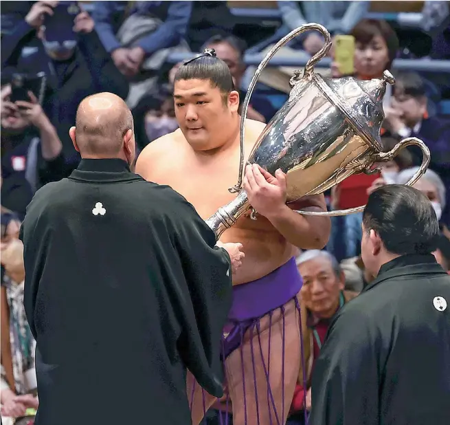  ?? The Yomiuri Shimbun ?? No. 17 maegashira Takerufuji receives the Emperor’s Cup after his historic win at the Spring Grand Tournament on March 24 in Osaka.