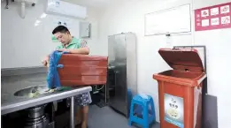  ??  ?? Kitchen waste is poured into a disposal unit. Machines have been installed in communitie­s all over Putuo. — Jiang Xiaowei