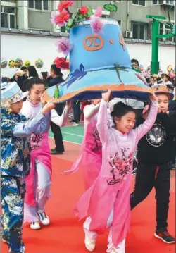  ?? PROVIDED TO CHINA DAILY ?? Students from Qinglongji­e Primary School in Jinan, Shandong province, parade across campus on Thursday with a giant hat they made by hand. The activity was part of a science festival at the school.