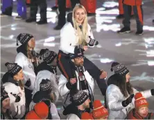  ?? Ryan Pierse / Getty Images ?? Lindsey Vonn catches a ride as Team USA walks during the Parade of Athletes at the Closing Ceremony.