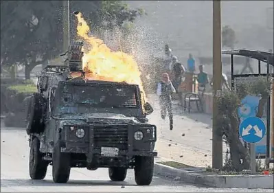  ?? ABBAS MOMANI / AFP ?? Un vehicle militar israelià és atacat amb còctels molotov en un assentamen­t jueu a prop de Ramal·lah