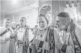  ?? Cengiz Yar / Associated Press ?? Priests lead a Christmas Eve Mass in the Assyrian Orthodox church of Mart Shmoni in Bartella, Iraq. The church was torched when ISIS seized the town in 2014. It is still missing its icons and most of its light fixtures.