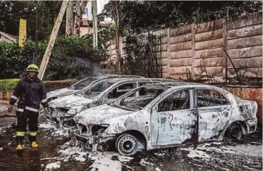  ??  ?? ANGGOTA bomba memeriksa beberapa kereta yang musnah akibat letupan bom. - AFP