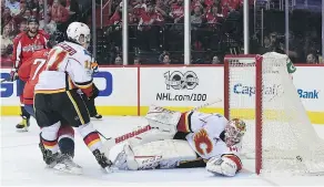  ?? — THE ASSOCIATED PRESS ?? Defended by centre Mikael Backlund, centre, Washington winger T.J. Oshie, left, fires a shot past Calgary goalie Brian Elliott during the second period Tuesday in Washington.