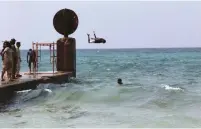  ?? (Reuters) ?? A MAN JUMPS into the sea as members of the Libyan National Army stand guard in Sabri, a central Benghazi district, this week.