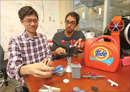  ?? GREG GILBERT, SEATTLE TIMES ?? Justin Chan, left, and Vikram Iyer show plastic devices they 3D printed that have no batteries, but can communicat­e over a WiFi network.