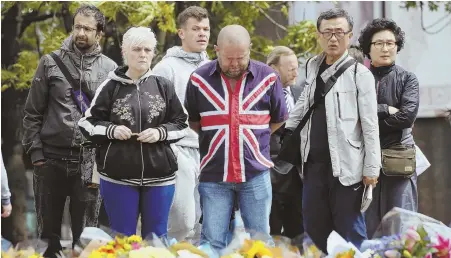  ?? AP PHOTOS ?? IN MOURNING: People look at flowers near London Bridge, above, while a woman prepares to leave a bouquet of flowers at a floral tribute yesterday.