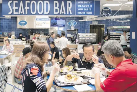  ??  ?? People eat at the seafood bar at T&amp;T Supermarke­t’s newest location, Richmond, this week. Shoppers can buy fresh seafood in the store and have it steamed or baked to be eaten on site.