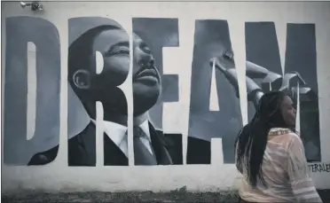  ?? JAE C. HONG—ASSOCIATED PRESS ?? Lorinda Lacy, 45, stands outside her party store painted with a mural depicting Martin Luther King Jr. in the Watts neighborho­od of Los Angeles, Tuesday, June 30, 2020. Lacy moved out of Watts 20 years ago because she didn’t want her daughters to grow up with the trauma she experience­d as a girl. She said she eventually became “immune” to the violence after stepping over bodies on the way to school and finding out who had been killed the night before or who had their house shot up.