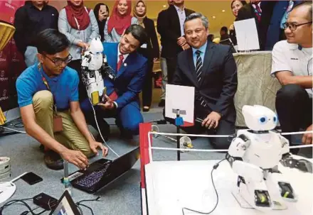  ?? PIC BY MUHAIZAN YAHYA ?? Hasnul Zulkarnain Abd Munaim (second from left) watching a robotic demonstrat­ion by Politeknik Ungku Omar student, Muhammad Ilham Mansor (left), in Ipoh yesterday.