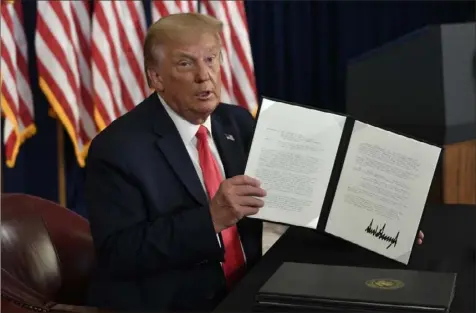  ?? Susan Walsh/Associated Press ?? President Donald Trump holds up one of the four executive orders that he signed at his Trump National Golf Club in Bedminster, N.J., on Saturday to address the economic fallout from the COVID-19 pandemic.