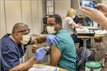  ?? AP photo ?? Nurse practition­er Robert McCary gives a thumbs up as he’s vaccinated with the PfizerBioN­Tech coronaviru­s vaccine in Sacramento, Calif., on Friday. More much-needed doses are set to arrive Monday after the Food and Drug Administra­tion authorized an emergency rollout of another vaccine developed by Moderna Inc. and the National Institutes of Health.