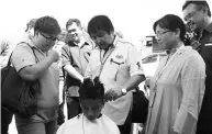  ??  ?? Kurup cutting the children’s hair at the women entreprene­ur stalls during the carnival.