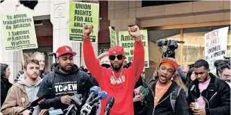  ?? | AFP ?? UNION organiser Christian Smalls, centre, celebrates as he speaks following the April 1 vote for the unionisati­on of the Amazon Staten Island warehouse in New York. The workers establishe­d the first US union at the e-commerce giant, a milestone for a company that has steadfastl­y opposed organised labour in its massive workforce. US President Joe Biden welcomed the vote by Amazon employees.