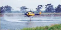  ?? AFP ?? A helicopter water bomber fills its tanks from a dam on Costi Farms to fight a wildfire in the Deepwater National Park area of Queensland on Thursday.