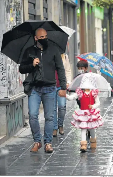  ?? ANTONIO L. JUÁREZ ?? Un padre acompaña a su hija con traje de gitana protegiénd­ose de la lluvia.