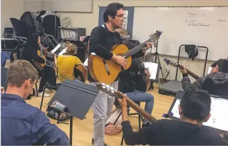  ??  ?? Spanish classical guitar instructor Ricardo Reyes Paz leads his class as it plays a song at Aspen Community Magnet School.