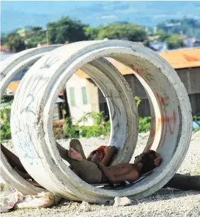  ?? ALDO NELBERT BANAYNAL ?? Two men get some rest and some respite from the scorching heat of the sun inside these culverts in Cebu City.