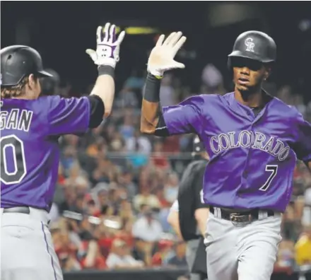  ?? Matt York, AP ?? Ryan Hanigan high-fives Raimel Tapia after Tapia hit a solo home run in the sixth inning of the Rockies’ series opener against the Diamondbac­ks in Phoenix on Friday night. Tapia’s homer at Chase Field helped the Rockies improve to 48-34.