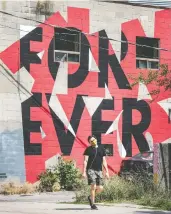  ?? PETER J THOMPSON / POSTMEDIA NEWS ?? A pedestrian in a mask walks past a mural on Toronto’s Wellington Street. Young people may be more pessimisti­c about this year than those older, a new poll indicates.