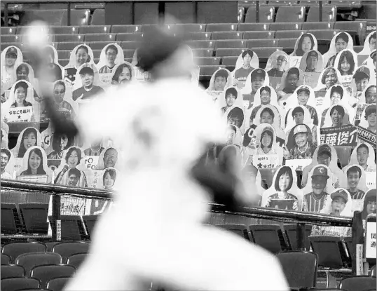  ?? KYODO NEWS VIA AP ?? Spectators’ seats are covered with large panels, carrying faces of fans with messages during an opening baseball game between Yokohama and Hiroshima on Friday.