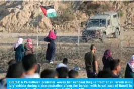  ??  ?? BUREIJ: A Palestinia­n protester waves her national flag in front of an Israeli military vehicle during a demonstrat­ion along the border with Israel east of Bureij in the central Gaza Strip on November 1, 2019. — AFP