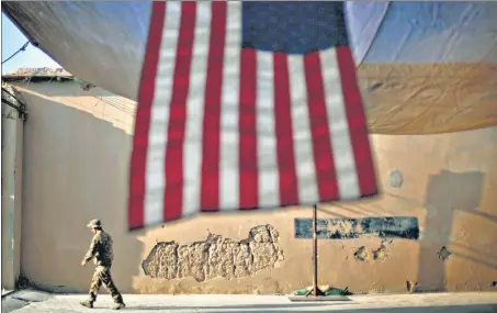  ?? AP ?? An American soldier walks past a US flag hanging in preparatio­n for an event marking the 10th anniversar­y of the 9/11 attacks, on September 11, 2011 in Kunar province.