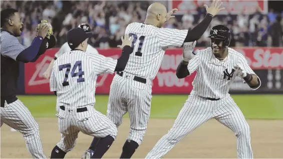  ?? AP PHOTO ?? LETS GET HIM: Miguel Andujar (right) is mobbed by his New York teammates after hitting a walkoff single in the ninth inning to beat the Indians last night at Yankee Stadium.