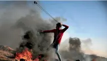  ??  ?? A Palestinia­n protester hurls stones towards Israeli soldiers near the Gaza Strip border with Israel.