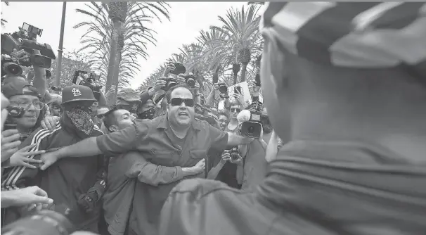  ?? DAVID MCNEW, GETTY IMAGES ?? News photograph­ers surround protesters against Donald Trump as one is held back in a confrontai­on with a Trump supporter, right, Wednesday outside a campaign rally by the presumptiv­e GOP presidenti­al candidate at the Anaheim Convention Center in...