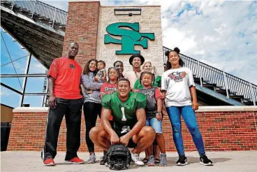  ?? [PHOTO BRYAN TERRY, THE OKLAHOMAN] ?? Edmond Santa Fe’s Trace Ford, center, poses with his family, from left, father Shaun Ford; sister Tawny Ford, 15; nephew Kylyn Burger, 7 months; sister Hayley Ford, 9; sister Destiny Ford, 22; brother Destin Ford, 19; sister Kiera Ford, 6; mother Desirae Ford; and sister Willa Ford, 12. Ford is one of the state’s top defensive ends.