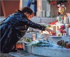  ?? IAN LANGSDON, EUROPEAN PRESSPHOTO AGENCY ?? A woman lights a candle at a makeshift memorial in front of city hall after a fatal hostage-taking incident at a church near Rouen, France, on Tuesday.