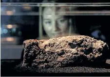  ?? DANIEL LEAL-OLIVAS/GETTY IMAGES ?? A Museum of London employee poses behind a piece of fatberg, a congealed lump of fat, sanitary napkins, wet wipes, condoms, diapers and similar items.