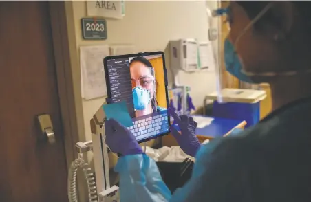  ?? Photos by Gabrielle Lurie / The Chronicle ?? Nurse Janessa Deleon sets up a tablet on a wheeled pole so a COVID19 patient can do a video chat with family members.