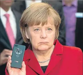  ?? JULIAN STRATENSCH­ULTE / AFP ?? Merkel, con un móvil en una feria en Hannover, en marzo del 2013