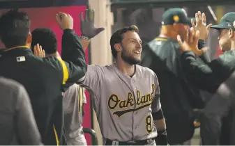  ?? Victor Decolongon / Getty Images ?? Oakland’s Jed Lowrie celebrates in the dugout with teammates after his solo home run in the fifth inning Saturday in Anaheim. He also homered in Friday’s game.