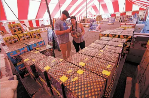  ?? PHOTOS BY LUIS SÁNCHEZ SATURNO/THE NEW MEXICAN ?? Anthony Reedy and his girlfriend, Jessica Pesterfiel­d, who were driving through the area Tuesday on their way to Memphis, Tenn., stopped to buy fireworks at the tent at Pojoaque Pueblo.