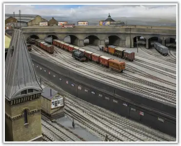  ??  ?? A view past the cemetery building spire into Kings Cross Goods Yard where a fish van train has just arrived. The extensive goods sheds can be seen to the left: an area of the model that has been extensivel­y developed over the last year. The Midland roundhouse can be seen behind York Way viaduct. The roundhouse was demolished in 1931: the model is an interestin­g exercise in perspectiv­e modelling.