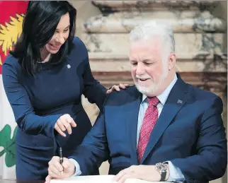  ?? PIERRE OBENDRAUF ?? Mayor Valérie Plante points to where Premier Philippe Couillard will sign the city’s Golden Book at a ceremony at Montreal City Hall on Thursday. The two met to discuss transit funding and other matters.