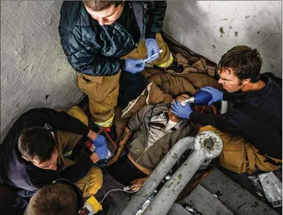  ?? SALWAN GEORGES / WASHINGTON POST ?? Manchester, N.H., firefighte­rs try to revive a man who overdosed in a building’s stairwell last year.