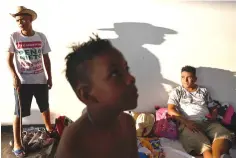  ??  ?? Caravan member Brandon Garcia, right, 21, of El Salvador rests in Juchitan, Mexico, on Tuesday. His son Caleb Isaac Flores, 7, centre, broke both of his arms climbing a tree earlier on the journey. The asthmatic boy also had a violent cough, and no inhaler.