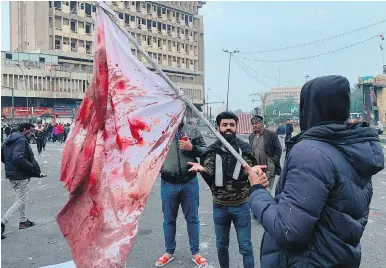  ?? THE ASSOCIATED PRESS ?? A protester holds a bloodstain­ed flag at Khilani Square in Baghdad on Saturday after gunmen killed 25 people and wounded more than 130 in an attack the previous evening.