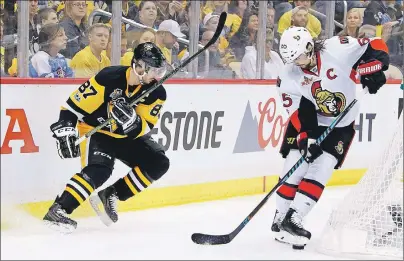  ?? CP PHOTO ?? Ottawa Senators’ Erik Karlsson (right) kicks at the puck after getting it away from Pittsburgh Penguins’ Sidney Crosby during Game 1 of the Eastern Conference final in the NHL Stanley Cup playoffs on Saturday in Pittsburgh.