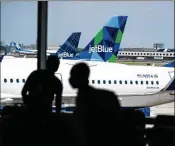  ?? MARK KAUZLARICH / BLOOMBERG ?? A JetBlue plane sits at a gate outside Terminal 5 at John F. Kennedy Internatio­nal Airport in New York. The carrier plans to add more seats at JFK.