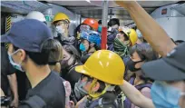  ?? KIN CHEUNG/ASSOCIATED PRESS ?? Protesters with protective gear take a train to another site for the two monthlong protest, in Hong Kong on Sunday.