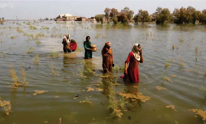  ?? Photograph: Fareed Khan/AP ?? Women wade through floodwater­s last year as they take refuge in Shikarpur district of Sindh province, Pakistan.