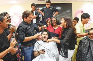  ?? Ahmed Ramzan/Gulf News ?? Fellow students cheer Lovish Manchanda as he gets his hair cut. A total of 21 boys and two male teachers had their hair shaved off while 16 girls had their hair cut. The hair was donated to FoCP.