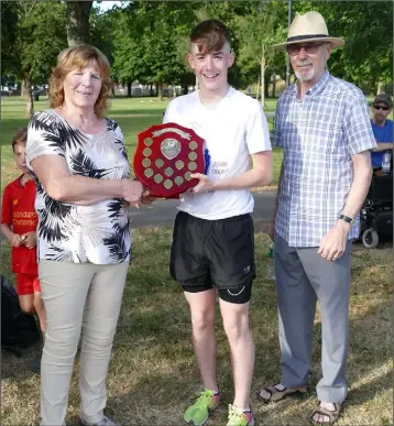  ??  ?? Adam O’Connor of United Striders receiving the Declan Shannon Perpetual Trophy from Kathleen and Michael Shannon after his victory in the inaugural race on Saturday.