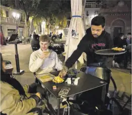  ?? Elisenda Pons ?? Un camarero atiende a unos clientes en una terraza de Barcelona.