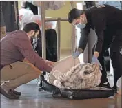  ?? Myung J. Chun Los Angeles Times ?? SECURITY GUARDS Nick Karwani, left, and Abdul Nasir screen the belongings of new residents.